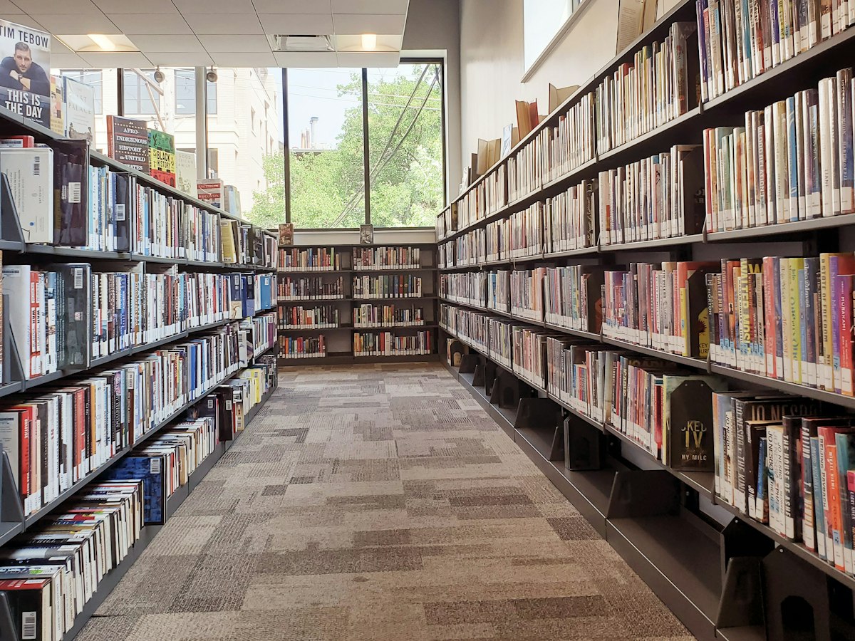 Library aisle between bookshelves with a commercial carpet tile floor