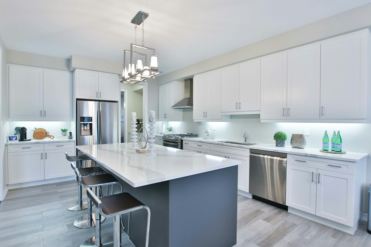 White kitchen with a large island, pendant lights and stainless appliances