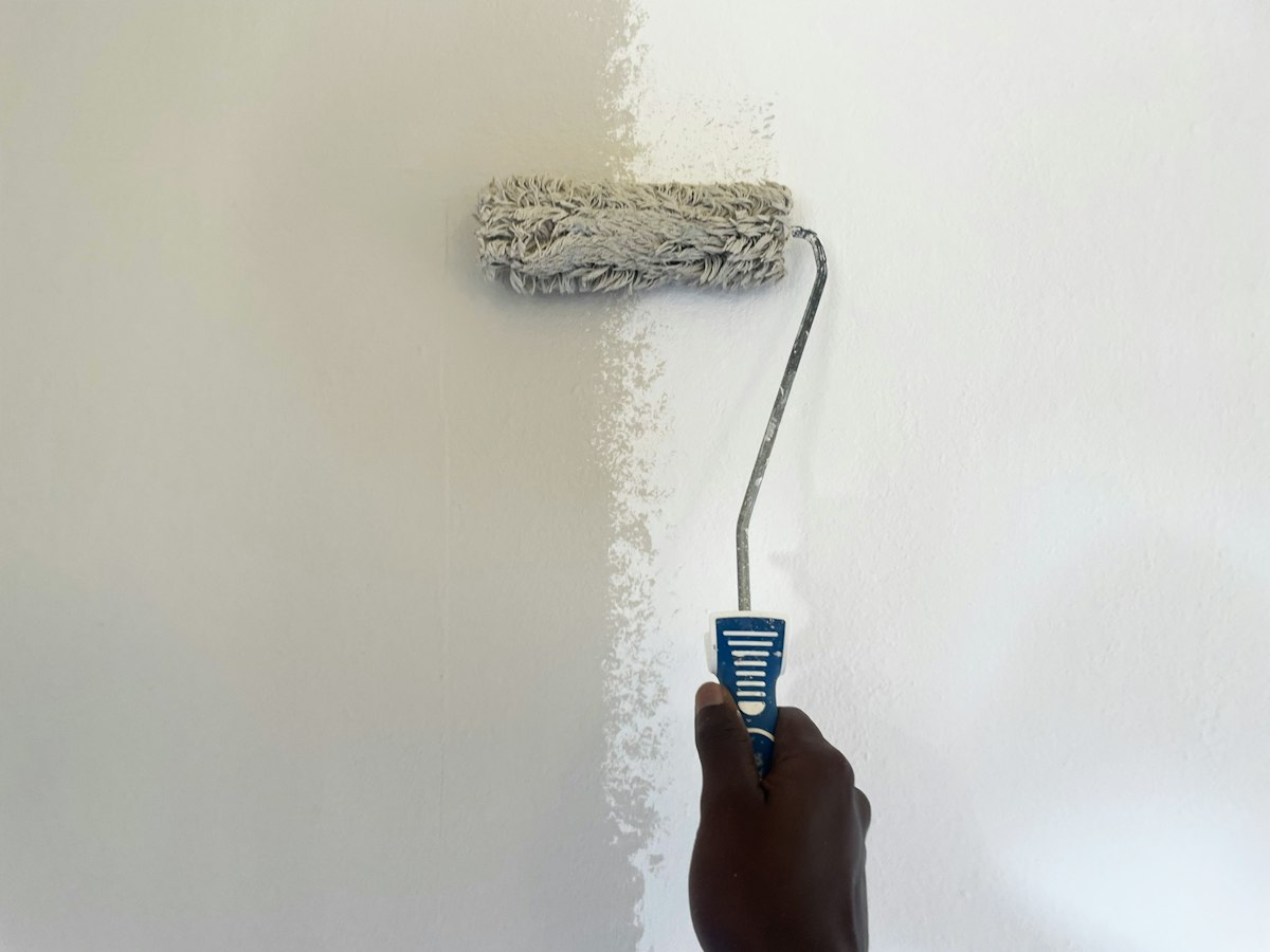 Paint roller applying a fresh coat to a smooth white wall