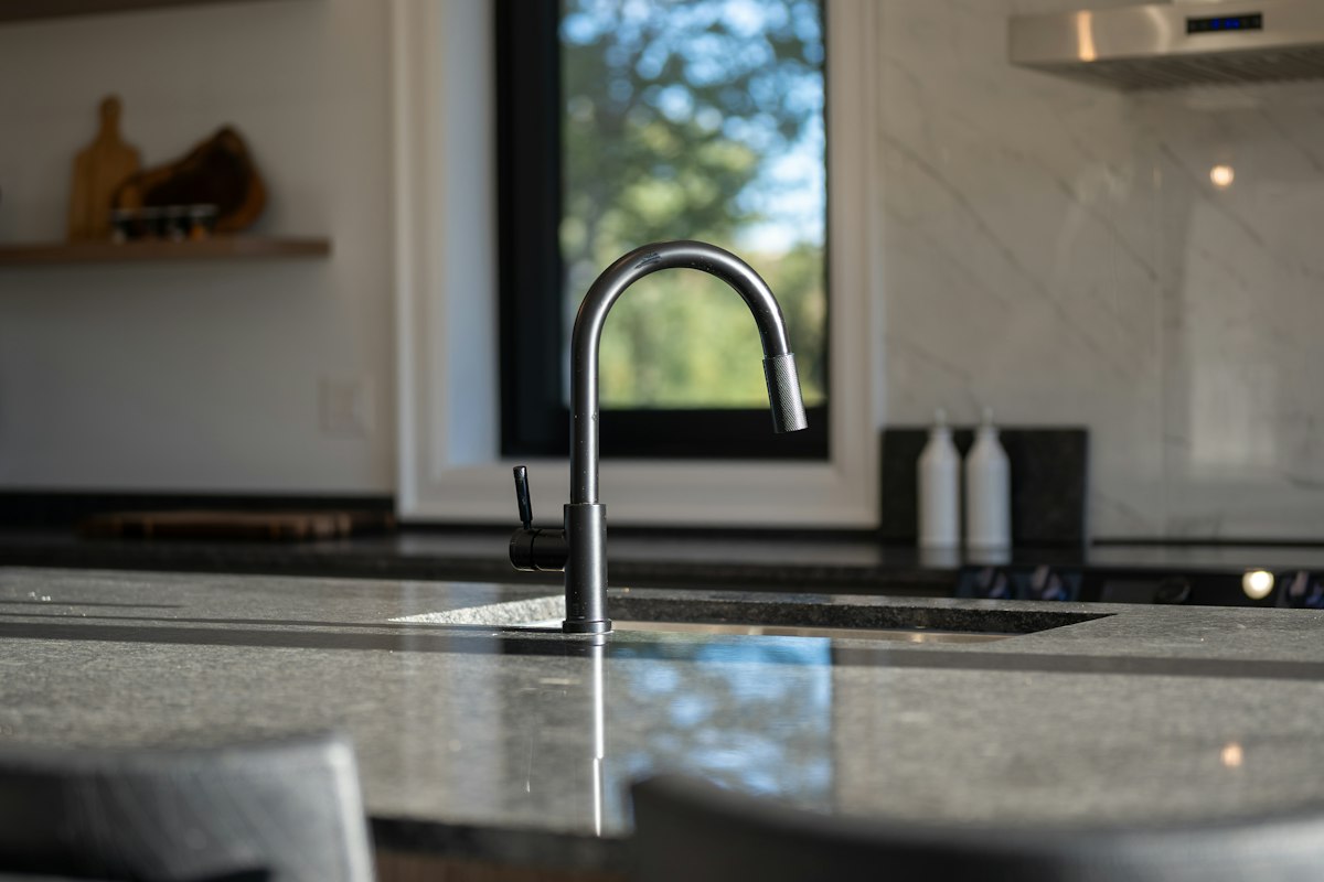 Kitchen faucet on a speckled stone countertop